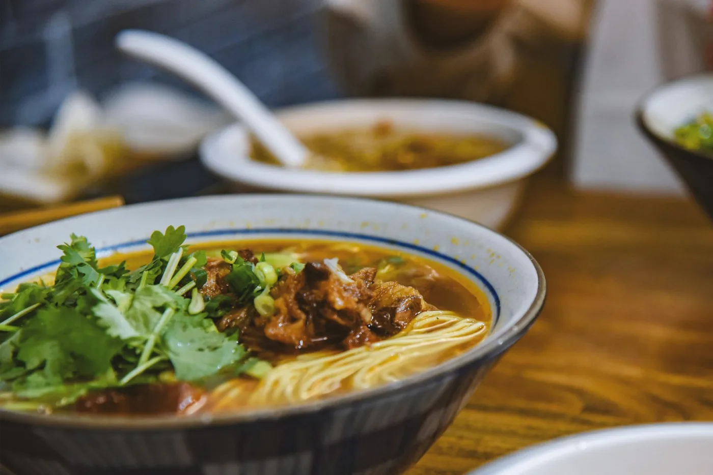Braised beef noodles in a red broth with fresh herbs